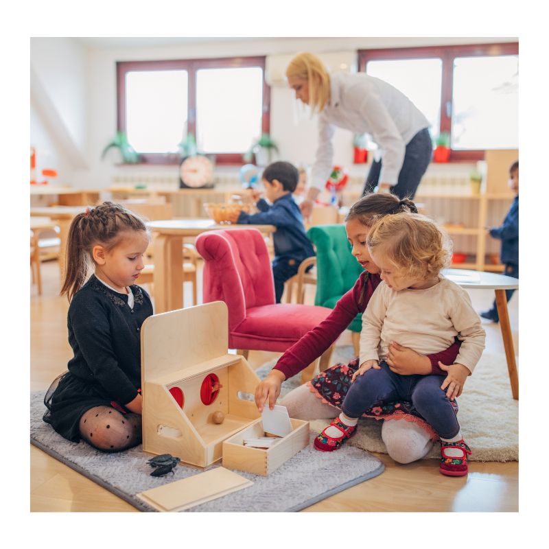 A teacher guiding PreK and multi-age students using early literacy manipulatives in a small micro-school classroom setting.
